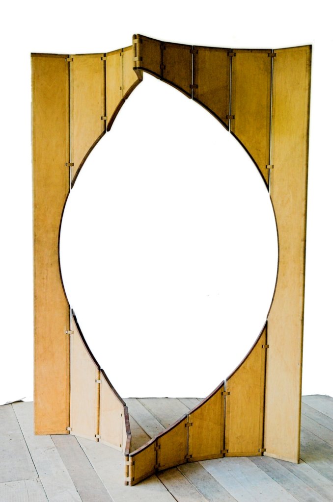 Visão frontal da escultura móvel Ó mostrando a abertura oval central quase completa entre os painéis verticais articulados.