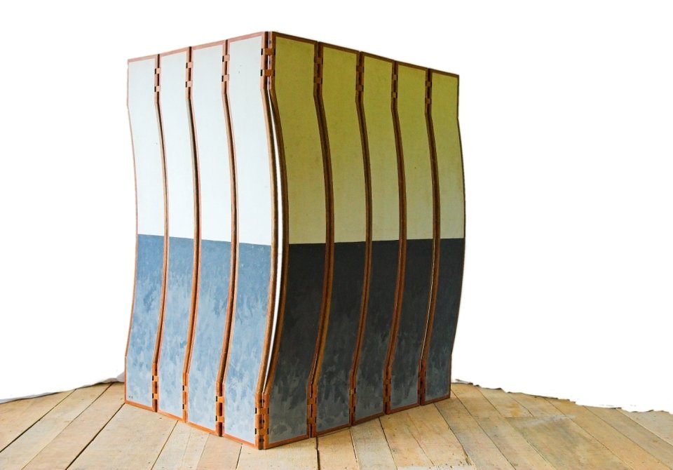 A escultura móvel Fêmea fechada em um bloco angular compacto sobre o piso de madeira.