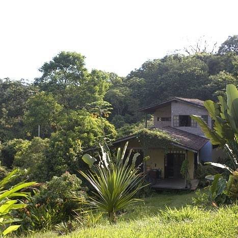 Casa de dois pavimentos entre árvores da montanha vista a partir do gramado.