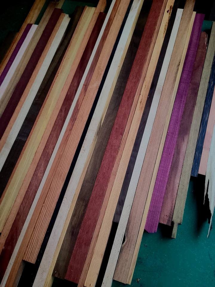 Fileira de ripas compridas de madeiras de tons e cores diferentes apoiadas lado a lado.