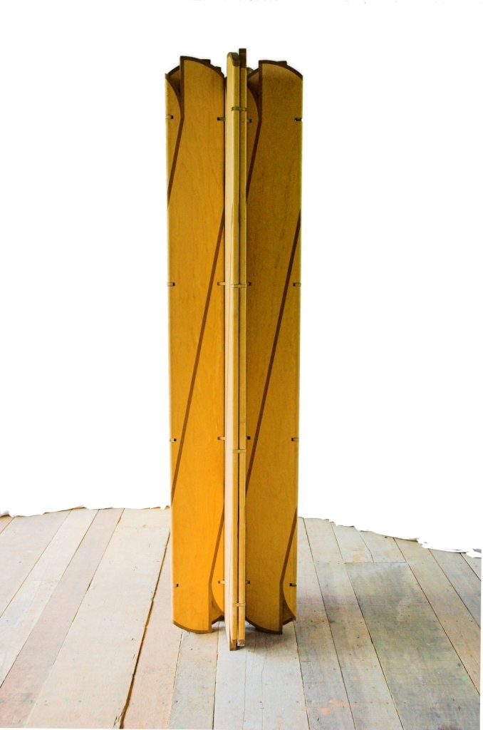 A escultura móvel Onda reunida em volume triangular vertical com linhas escuras nas faces de compensado.
