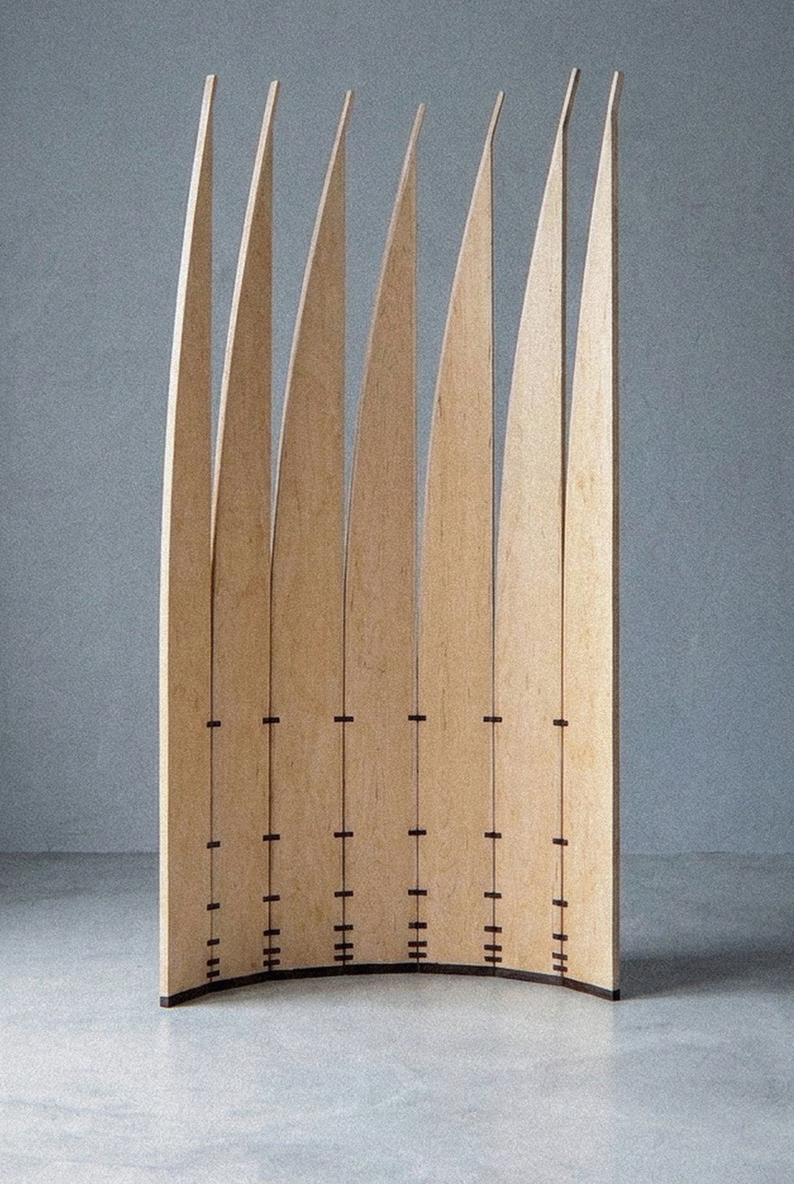A escultura móvel Velas vista de perto, em arco côncavo aberto com lâminas verticais de pontas curvadas.