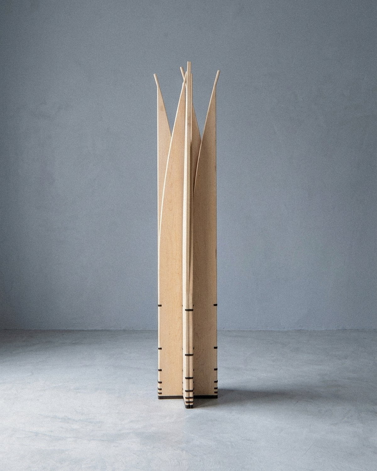 A escultura móvel Velas vista inteira à distância, aberta em estreita coluna radial com lâminas pontiagudas voltadas para fora.